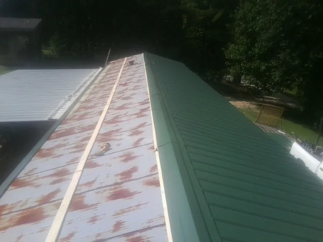 Old rusted panels beside newly installed green metal roofing — Wind Damage Roof Repair by Roofing Brothers in Coosawhatchie