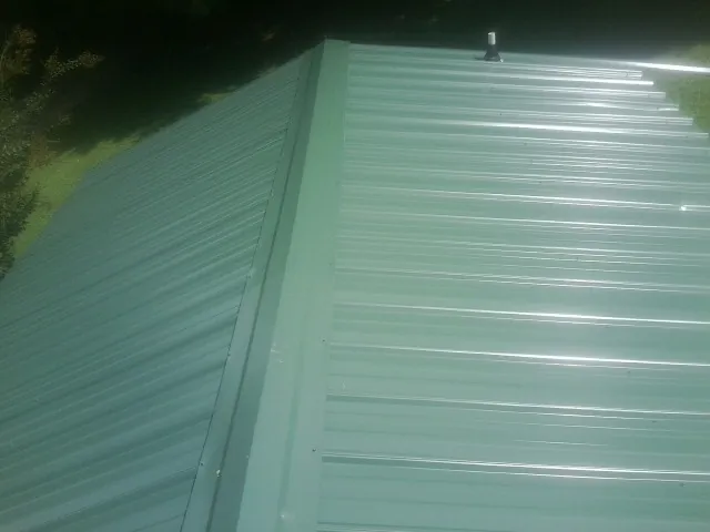 New green metal panels meeting at the ridge of a roof — Flat Roof Repair work by our crew in Coosawhatchie
