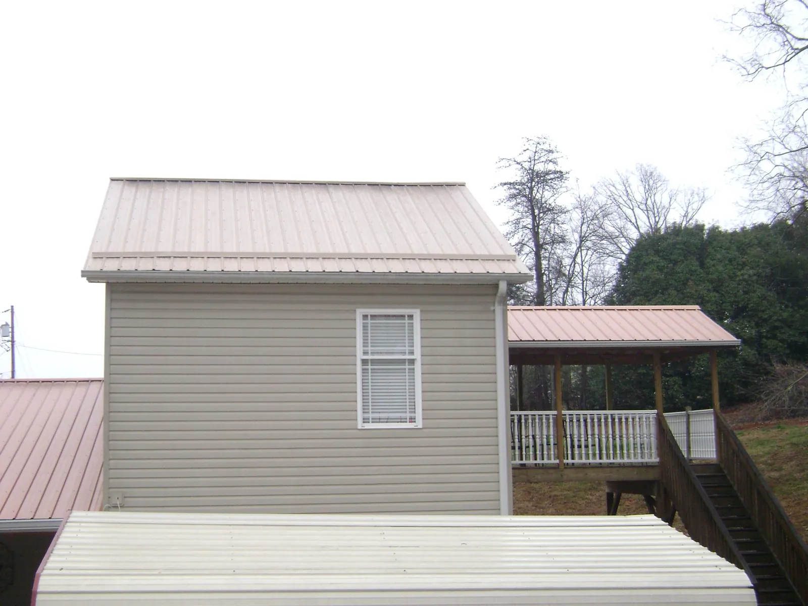 Tan metal roofs on a two story addition and attached porch, from a Roof Replacement job in Coosawhatchie
