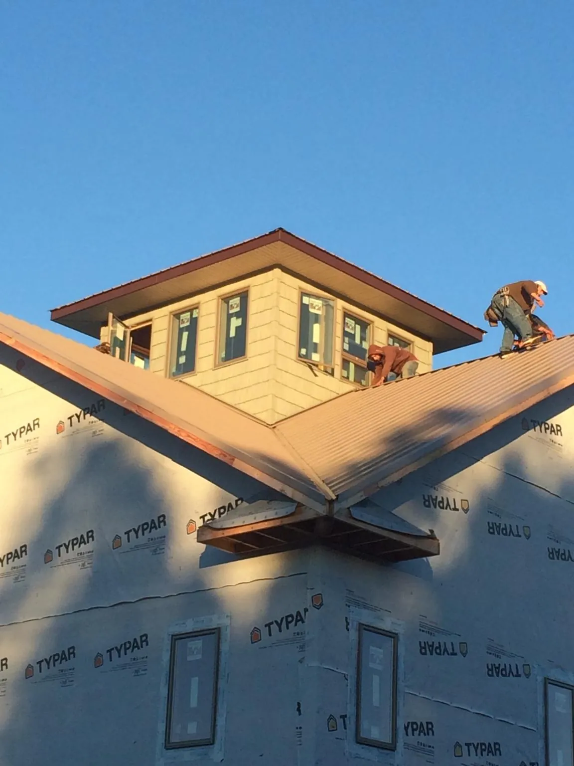Roofers working around a rooftop cupola on a new metal roof at sunset — Roof Waterproofing in Coosawhatchie by Roofing Brothers